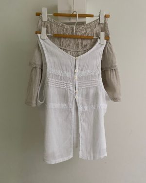 Blusa blanca sin mangas de lino con detalles de encaje y botones y apertura lateral